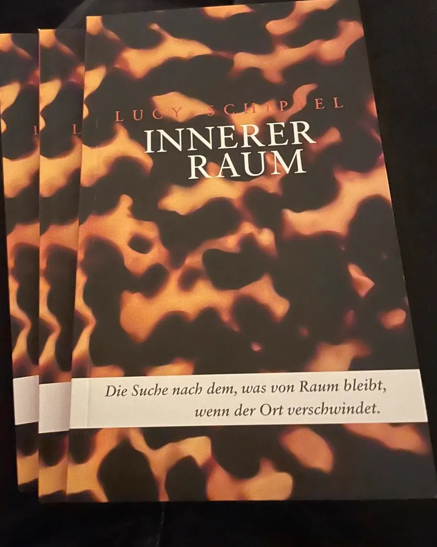 Drei gedruckte Exemplare von INNERER RAUM, aufgefächert. Three printed copies of INNERER RAUM, fanned out.